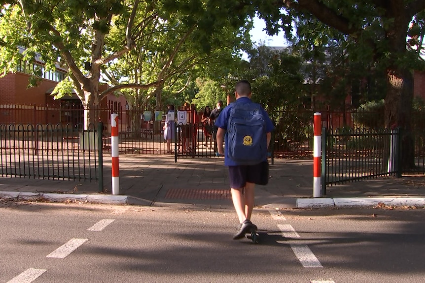 A boy rides a scooter across a school crossing