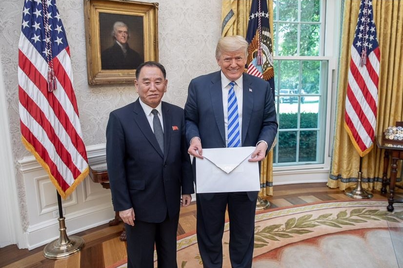 Kim Yong-chol and Donald Trump pose in the oval office with a large letter.