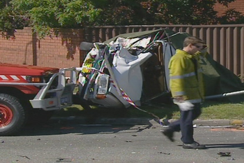 An emergency worker walks past the white sedan which was turned on its side in the fatal crash at Wilson
