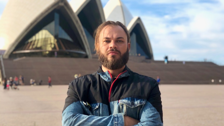 Man with his arms folded, standing with the Sydney Opera House in the background.