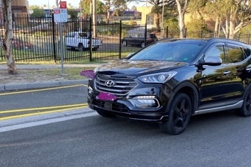 A black Hyundai SUV is stationary on a suburban street.