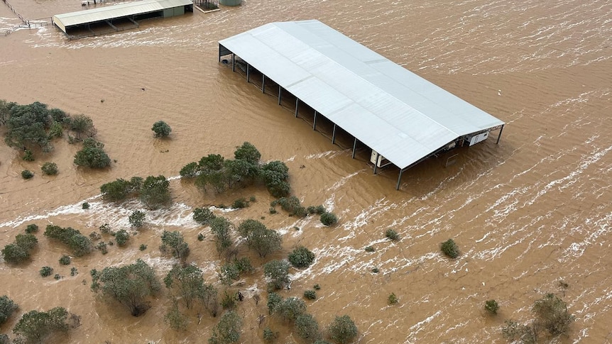 Aerial view of a large shed almost underwater due to flood. 