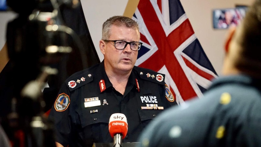NT Police Commissioner Jamie Chalker stands and looks concerned at a press conference.