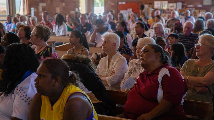 Multicultural parishioners sit in pews.