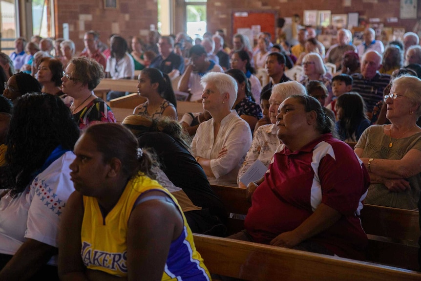 Multicultural parishioners sit in pews.