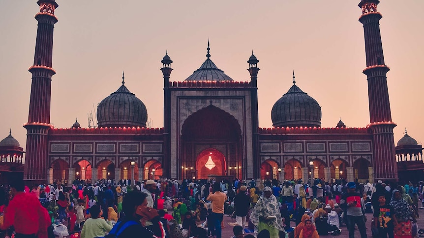 Hundreds of people gather at dusk outside a large mosque called Jama Masjid located in India.