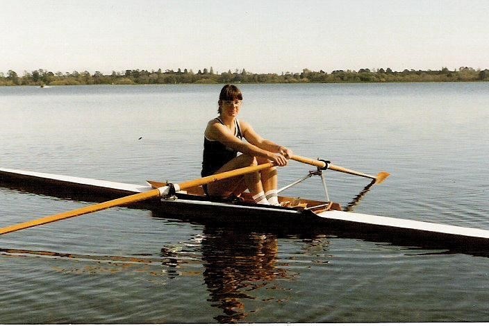 A young woman rowing on a lake.