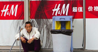 A cleaner sits outside retail giant H&M store in China.