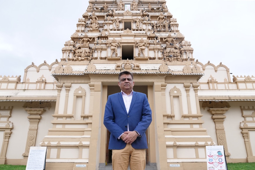 A man stands in front of a Hindu temple