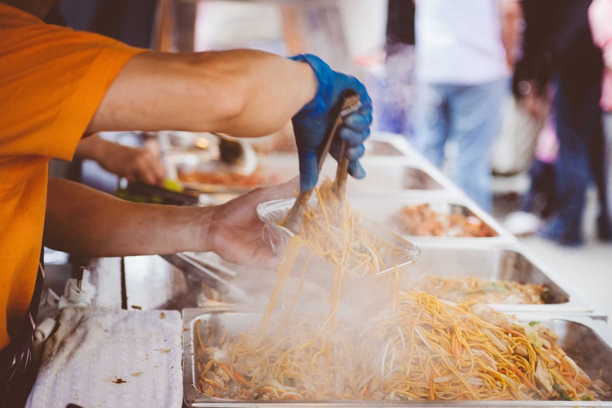 A big batch of noodles being served onto a plate at a chinese new year night market.