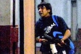 TV still of a man carrying an automatic rifle as he enters a train station in Mumbai