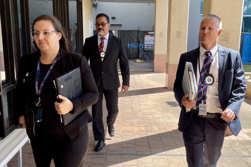 Three suited people looking important walking towards camera 