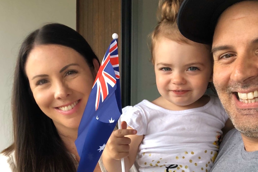 Erin Siqueira next to her child and her husband.