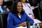 Judge Ketanji Brown Jackson smiles with her hands clasped during the first day of her Supreme Court confirmation hearing.