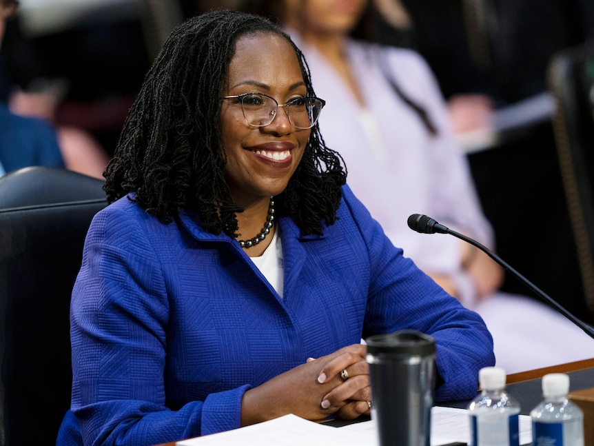 Judge Ketanji Brown Jackson smiles with her hands clasped during the first day of her Supreme Court confirmation hearing.