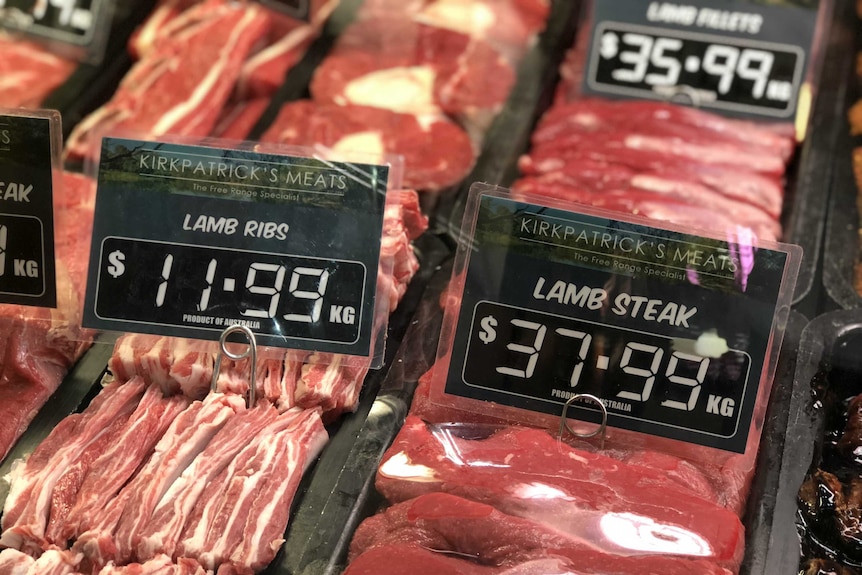 Lamb ribs and lamb steaks sit in a butchers counter with price tags above them