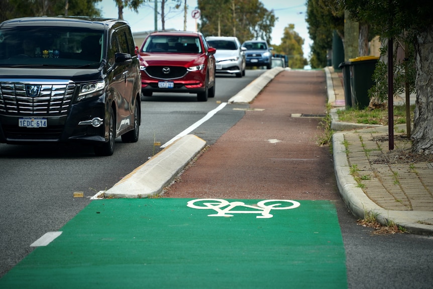 Cars drive down a street as a curb separated bicycle and vehiclar traffic