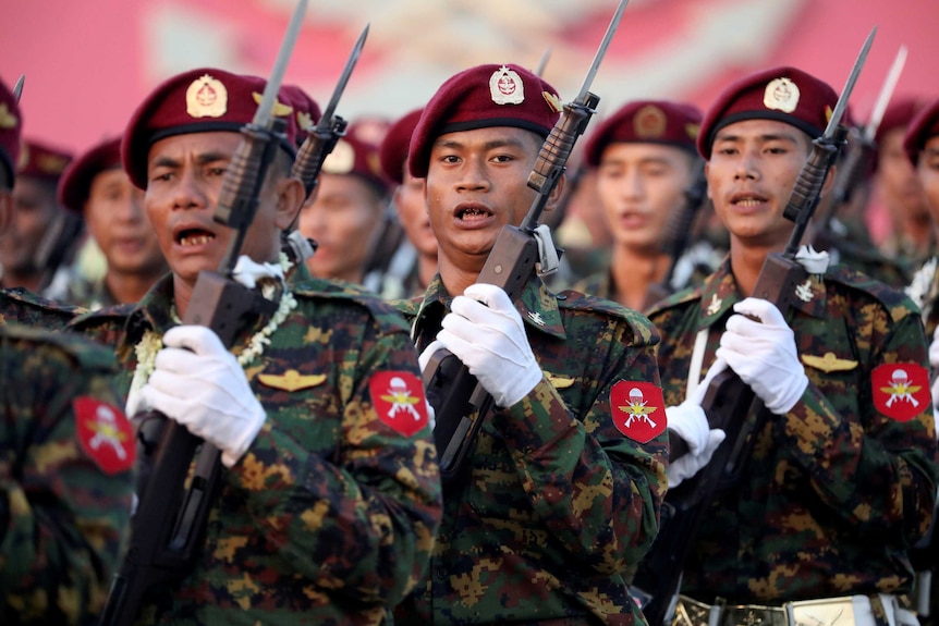 A group of soldiers with bayonets while wearing maroon berets