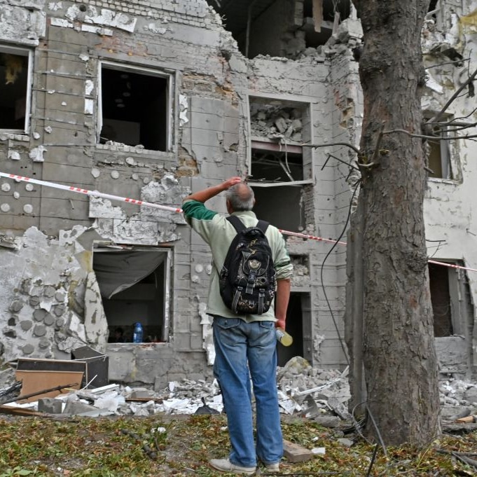 A man holds his head as he stands outside his apartment block, partially destroyed by a Russian missile strike