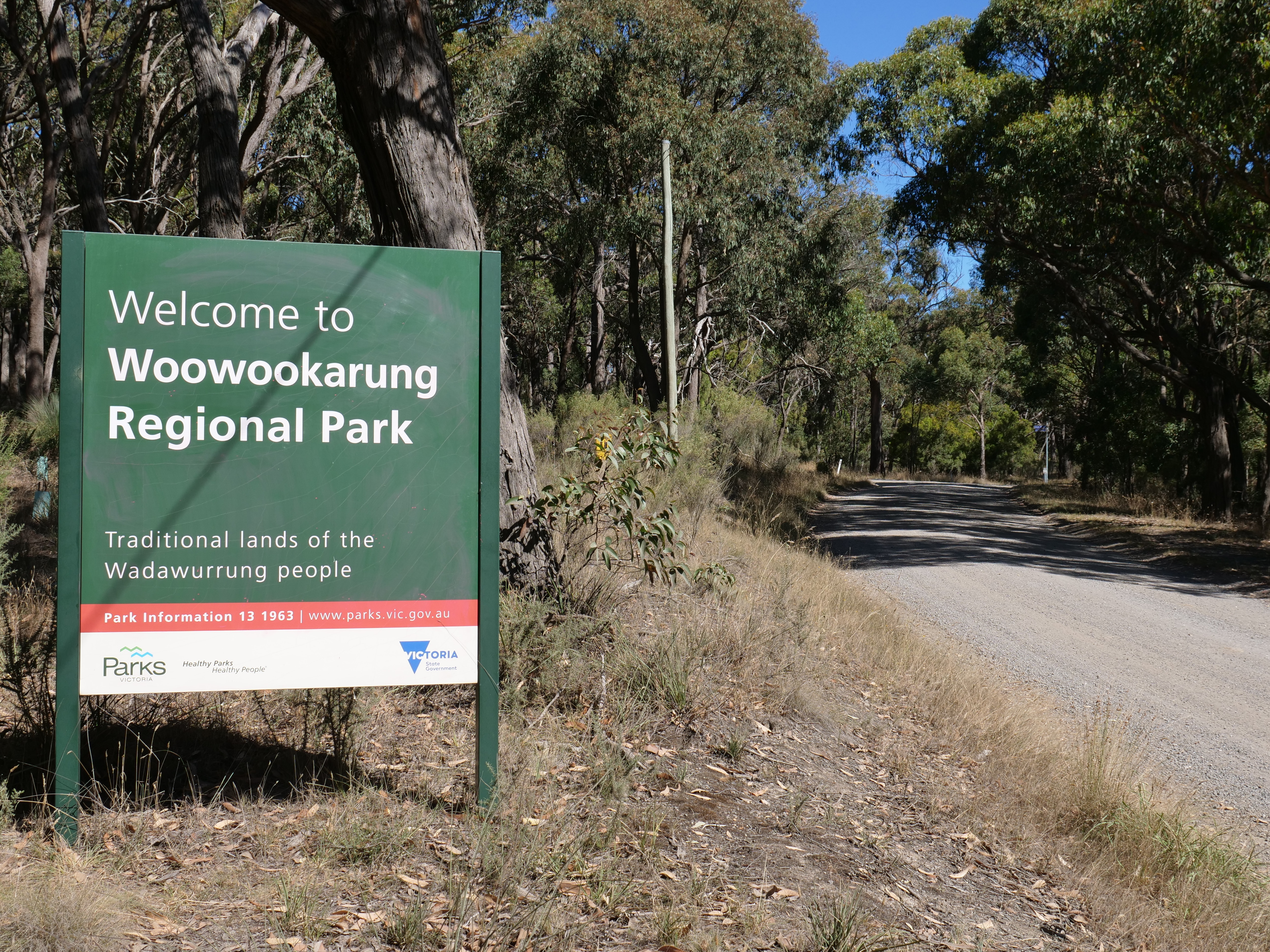 A sign that says Woowookarung Regional Park in front of bush.