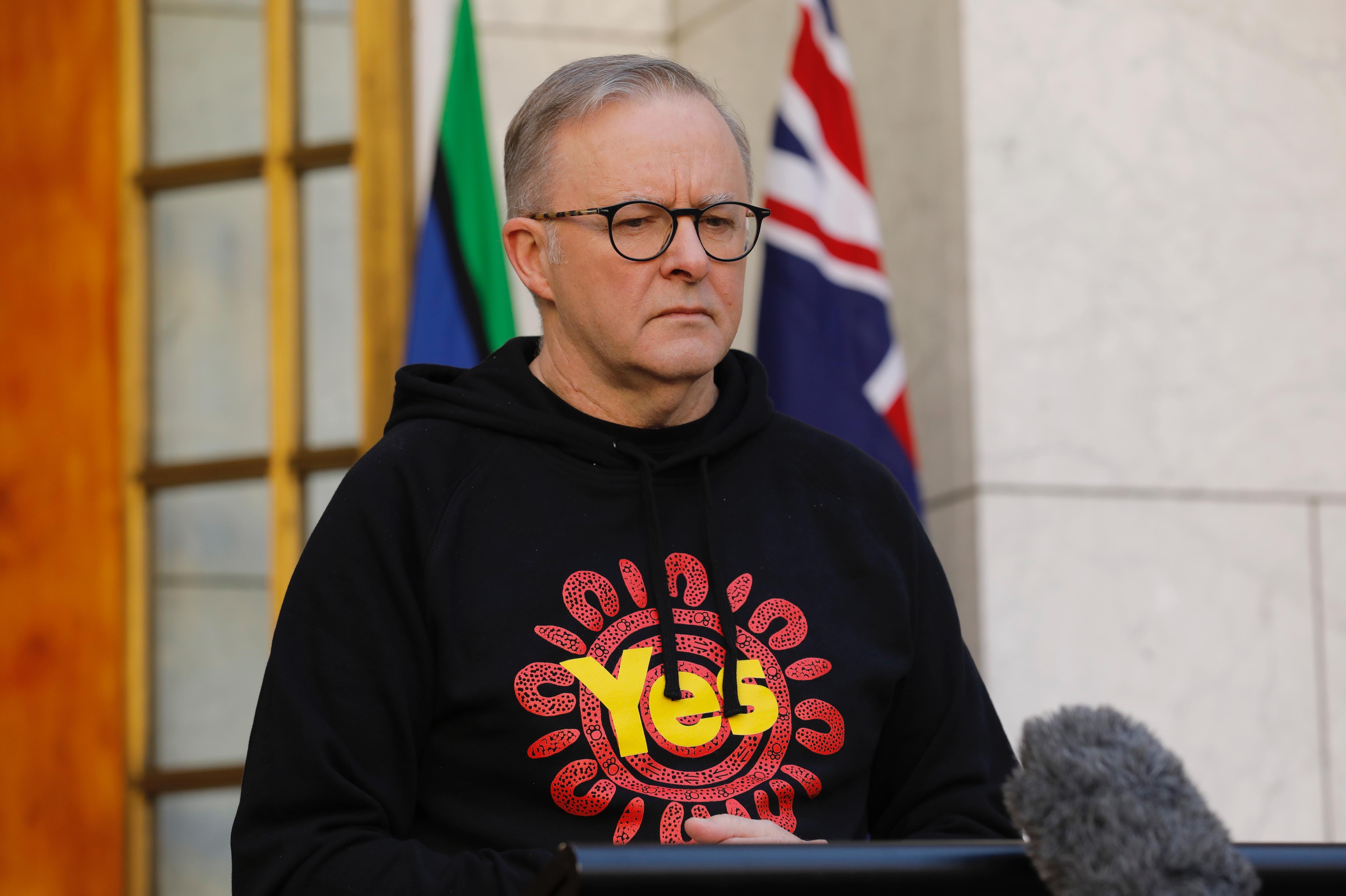 Albanese stands wearing a "Yes" Voice hoodie in the prime minister's courtyard, looking serious.
