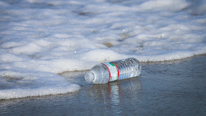 Plastic bottle being washed up on a beach