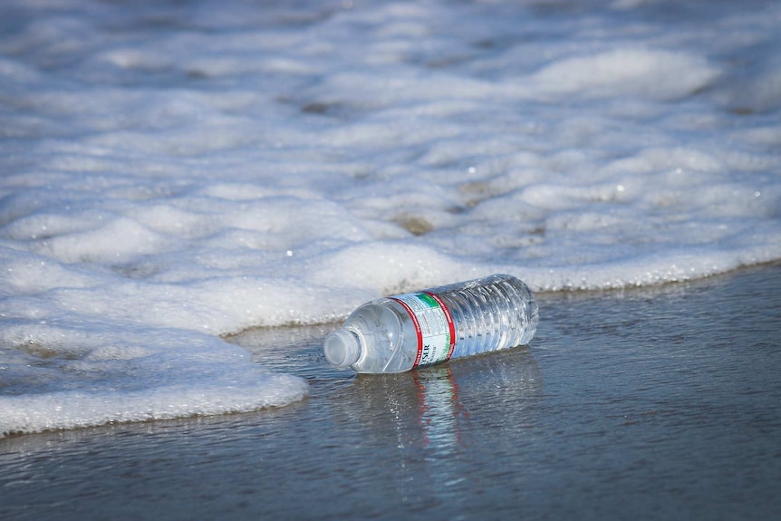 Plastic bottle being washed up on a beach