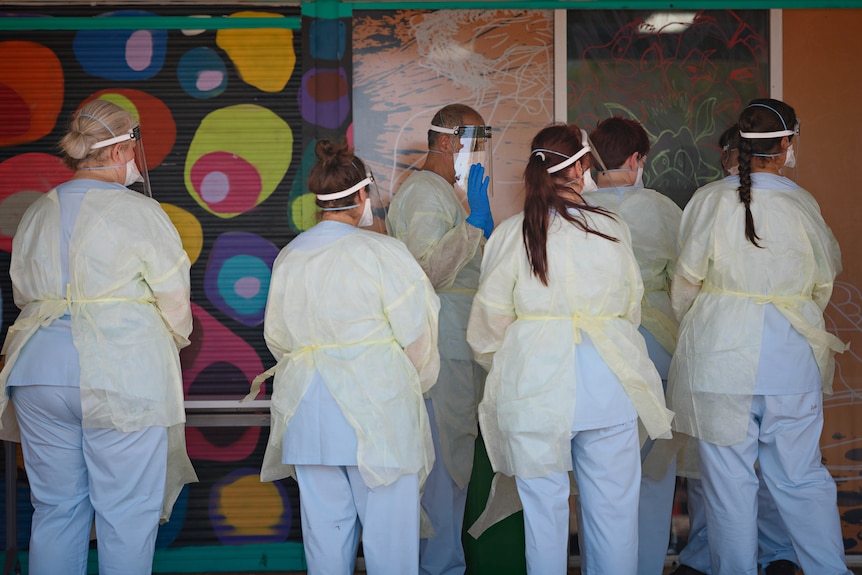 A group of people wearing full PPE outside a COVID testing site in Katherine.