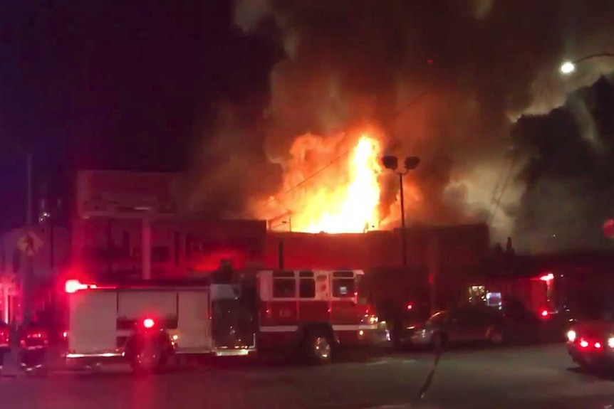 A wide view of flames and smoke as a warehouse burns.