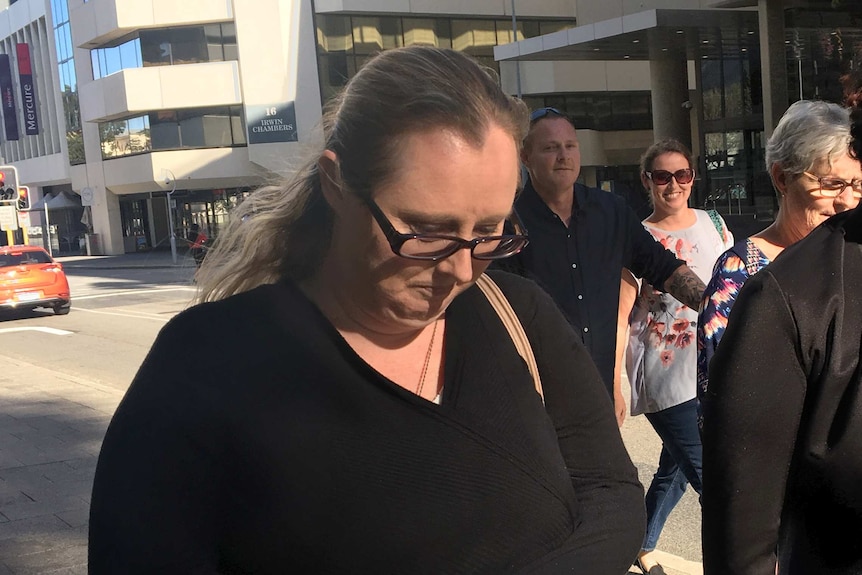 A mid-shot of Nicole Martin walking outside court in Perth with her head bowed wearing black.