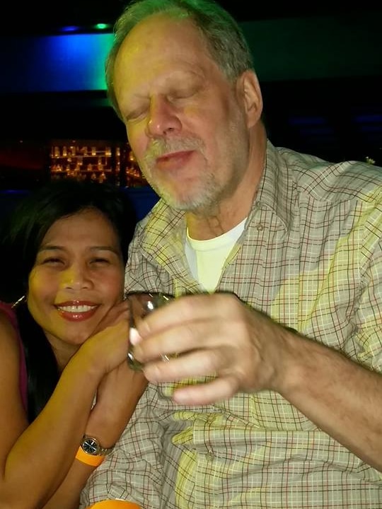 A man holds up a shot glass with a smiling woman on his arm.