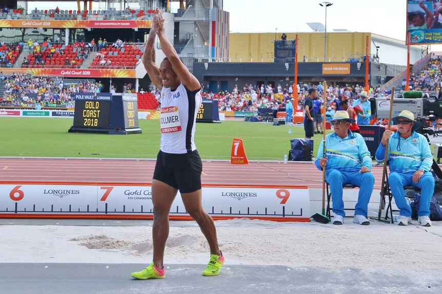 Eugene with his hands raised over his head after he finishes a jump.