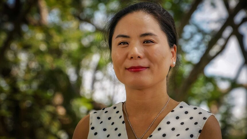 Aihua Feng stands in a white shirt.