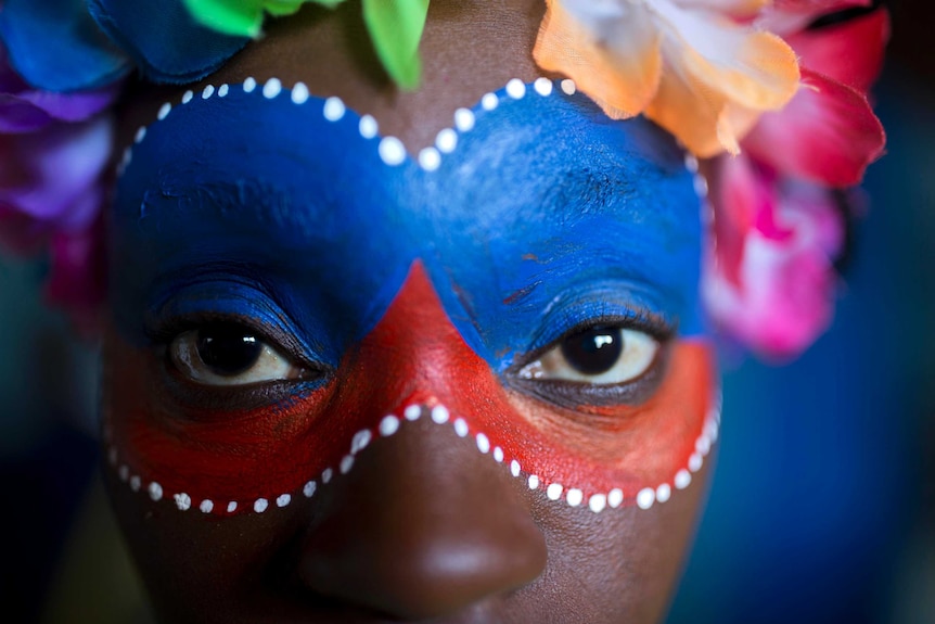 A close up of a carnival performer with bright face paint in Haiti.
