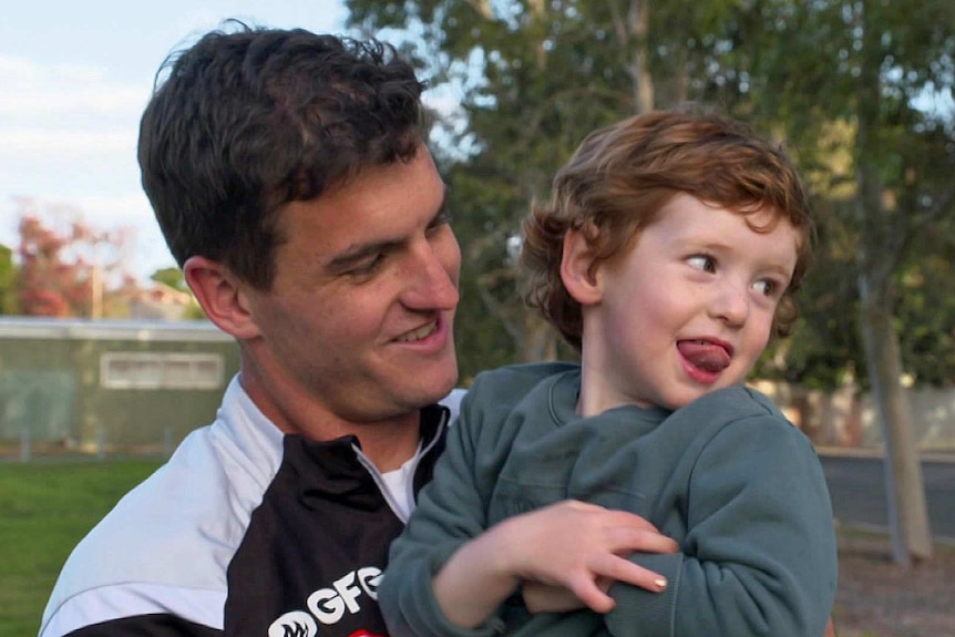 Tom Rockliff holds his son Jack in his arms.