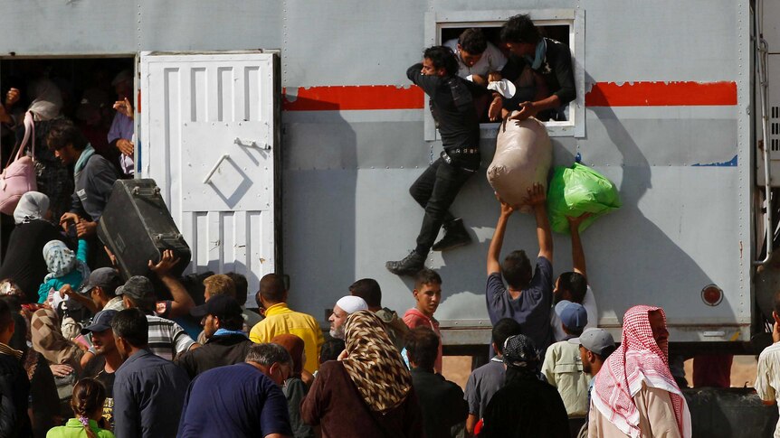 Refugees from Syria try to get a spot on a truck so they can travel back to their homeland