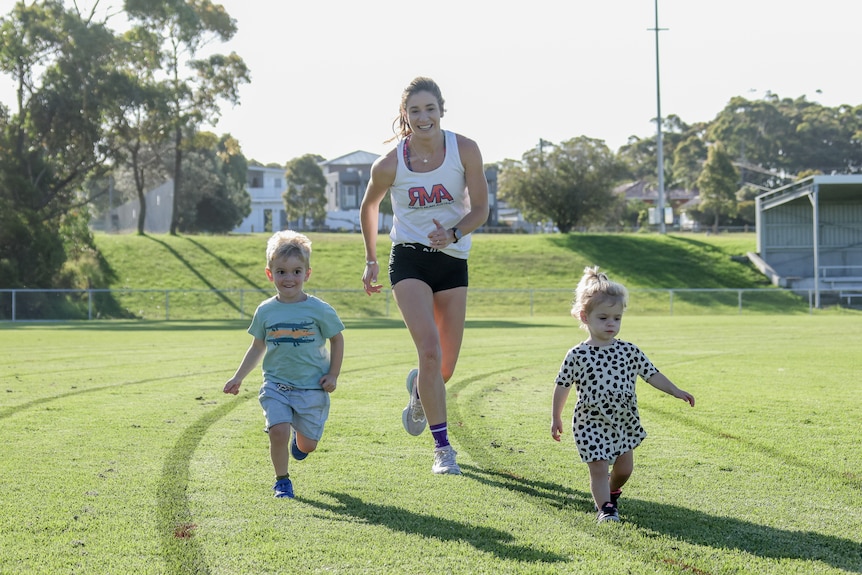 Amy O'Halloran runs with her children Henry and Jemima on a grass track.