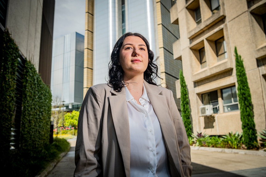 A young woman standing on the street, surrounded by high-rises.