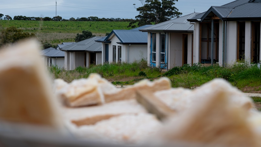 Houses under construction in the background with building materials in the foreground