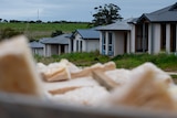 Houses under construction in the background with building materials in the foreground
