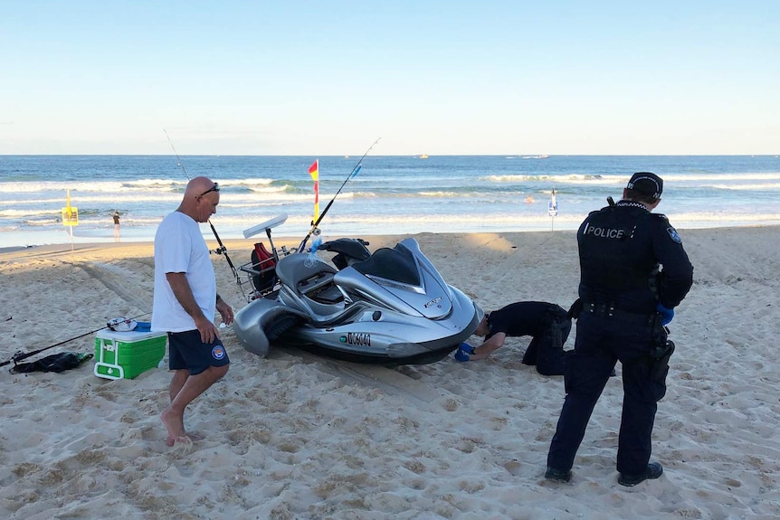 Police inspect the jet ski on the beach.