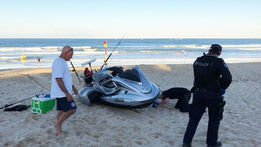 Police inspect the jet ski on the beach.