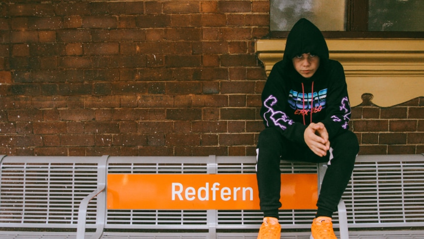 The Kid Laroi sitting on Redfern train station bench