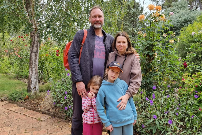 a man, his wife and two daughters in a garden.