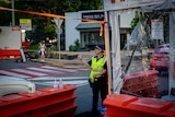 A police officer gives a thumbs up to a car driving through a checkpoint with orange barricades.