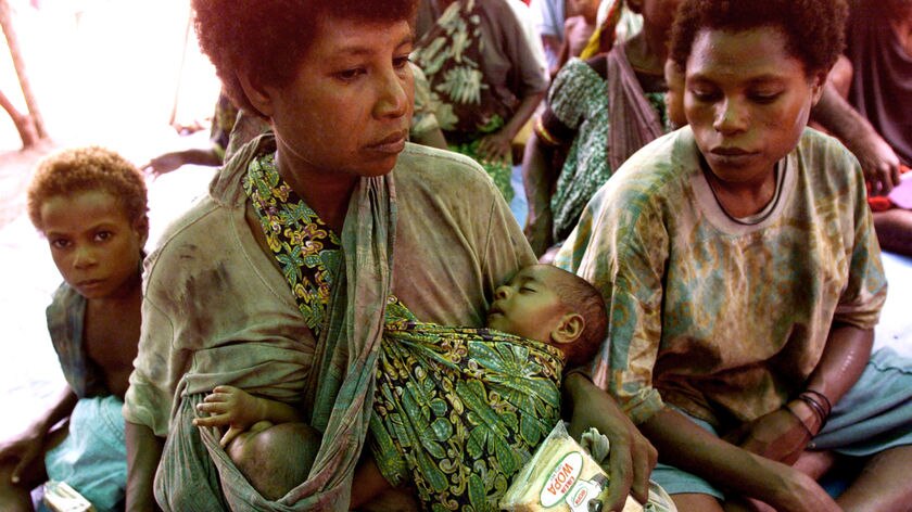 A mother sits at an aid station in PNG with her twins she saved from tidal waves which swept them from their Sissano home into a lagoon.