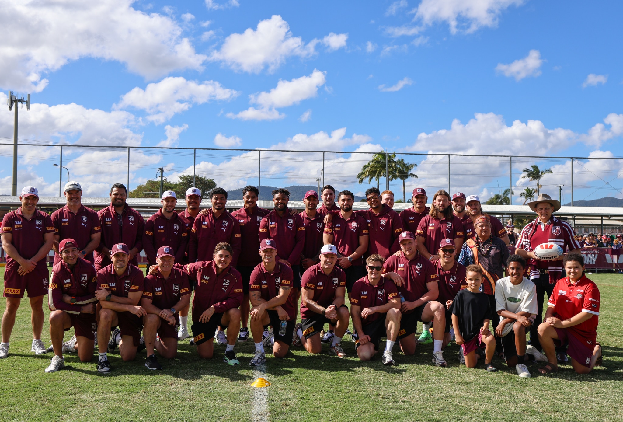 A football team in maroon pose for a team photo on a field