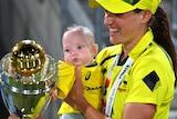 Megan Schutt holds her daughter Rylee as she stares at the shiny Cricket World Cup trophy