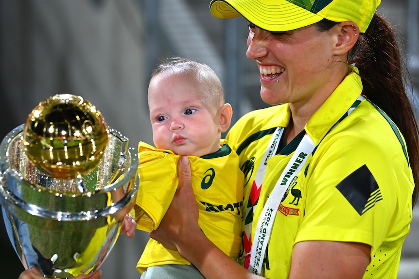 Megan Schutt holds her daughter Rylee as she stares at the shiny Cricket World Cup trophy