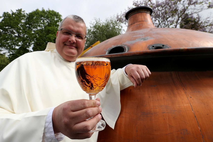 Father Karel poses with a Grimbergen beer, symbolised by a phoenix, in the courtyard of the Belgian Abbey of Grimbergen.